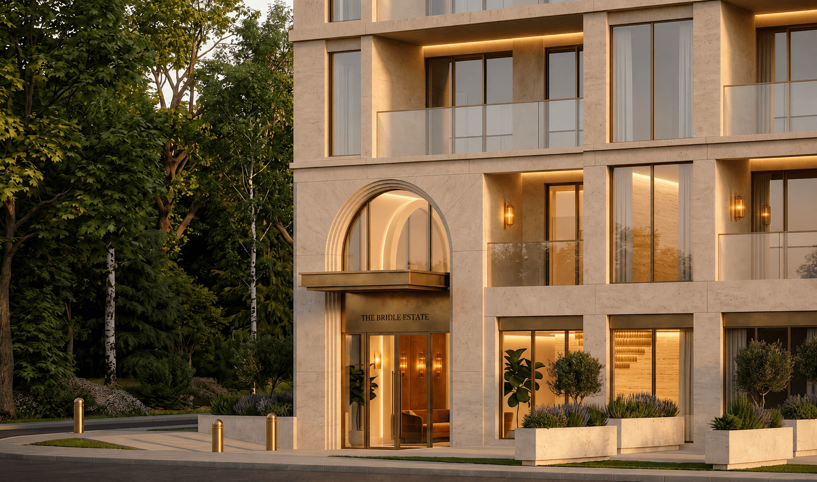 The Bridle Estate — arched limestone entrance glowing at dusk beside mature trees